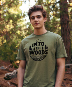 Model in hunter green cotton t-shirt hiking through woodland trail with dappled sunlight