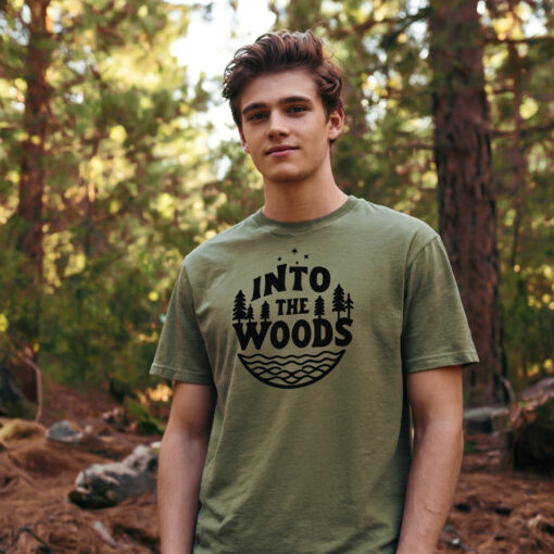 Model in hunter green cotton t-shirt hiking through woodland trail with dappled sunlight