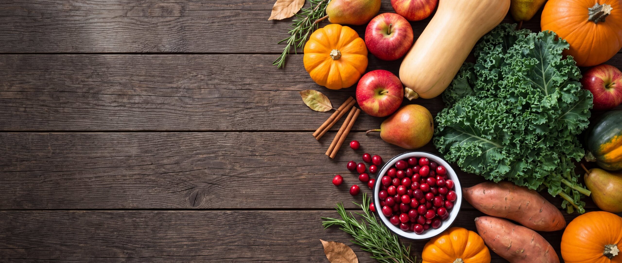 An October harvest on dark wood: pumpkins, squash, apples, kale and cranberries