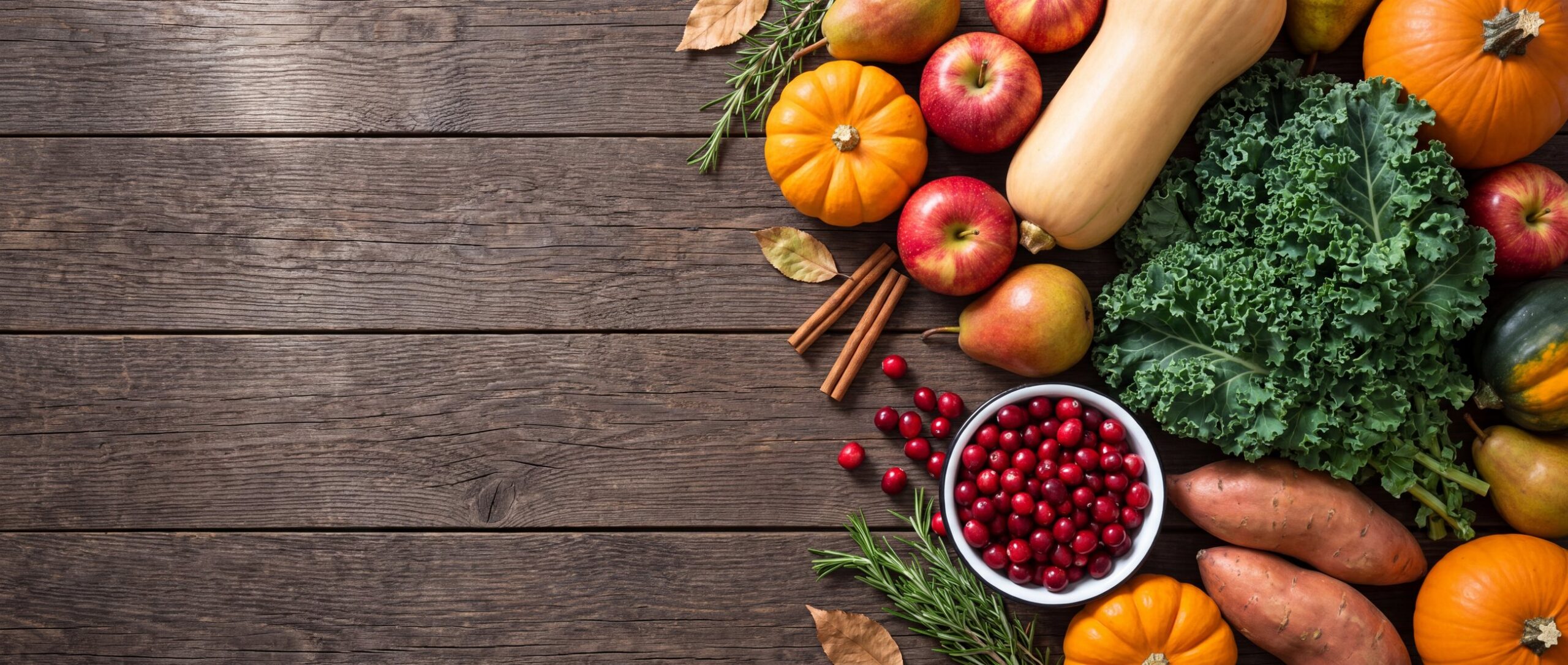 An October harvest: pumpkins, squash, apples, kale and cranberries on dark wood