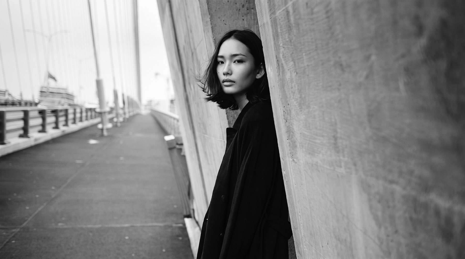 A model in the long coat on a New York bridge walkway
