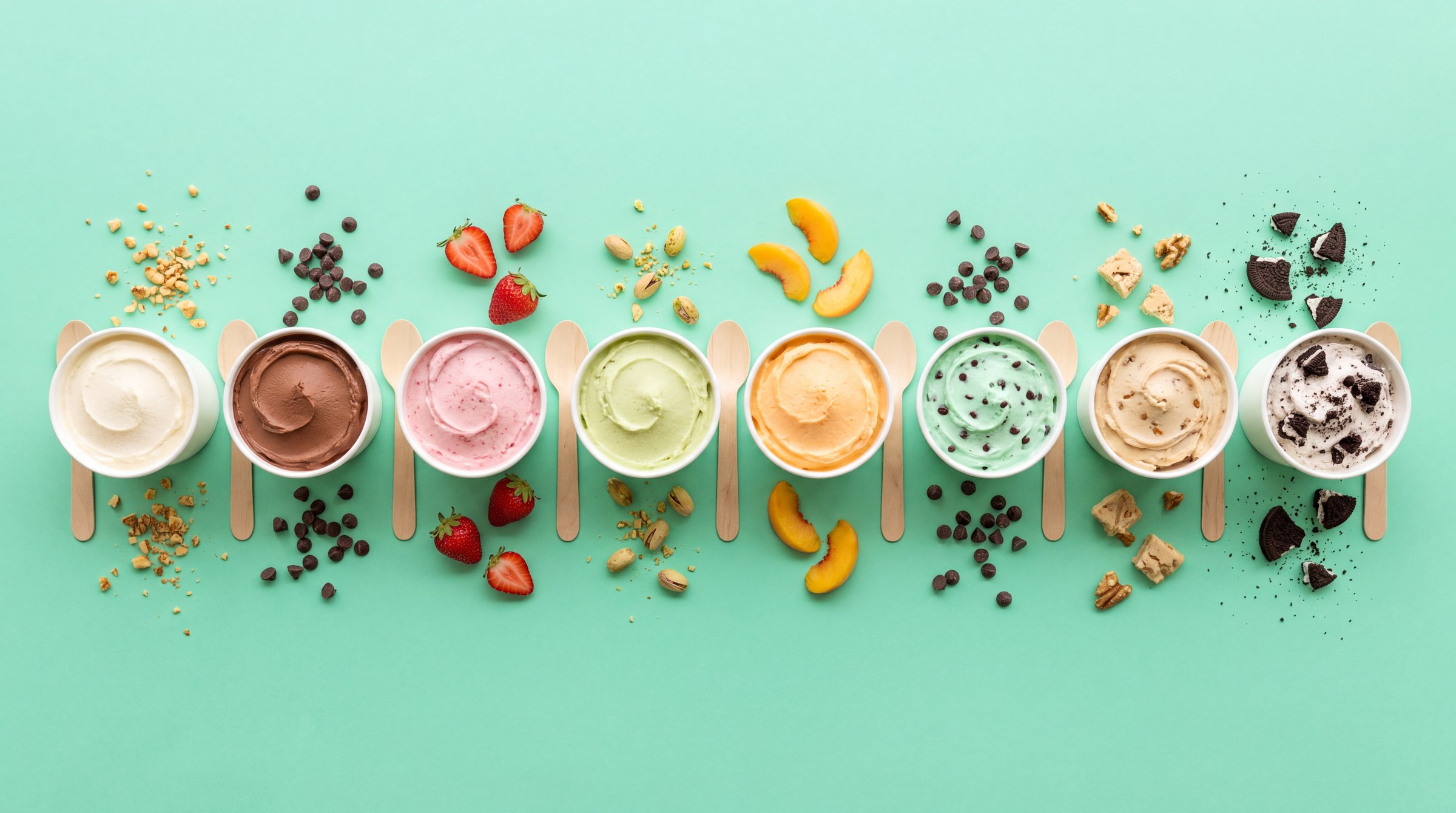 Eight little cups of frozen custard in a row on a mint table, each a different flavor