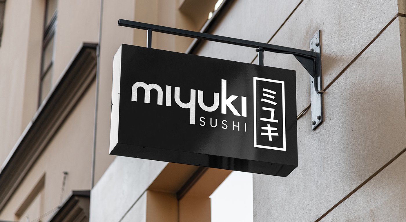 The black Miyuki Sushi sign on a bracket against a pale stone building