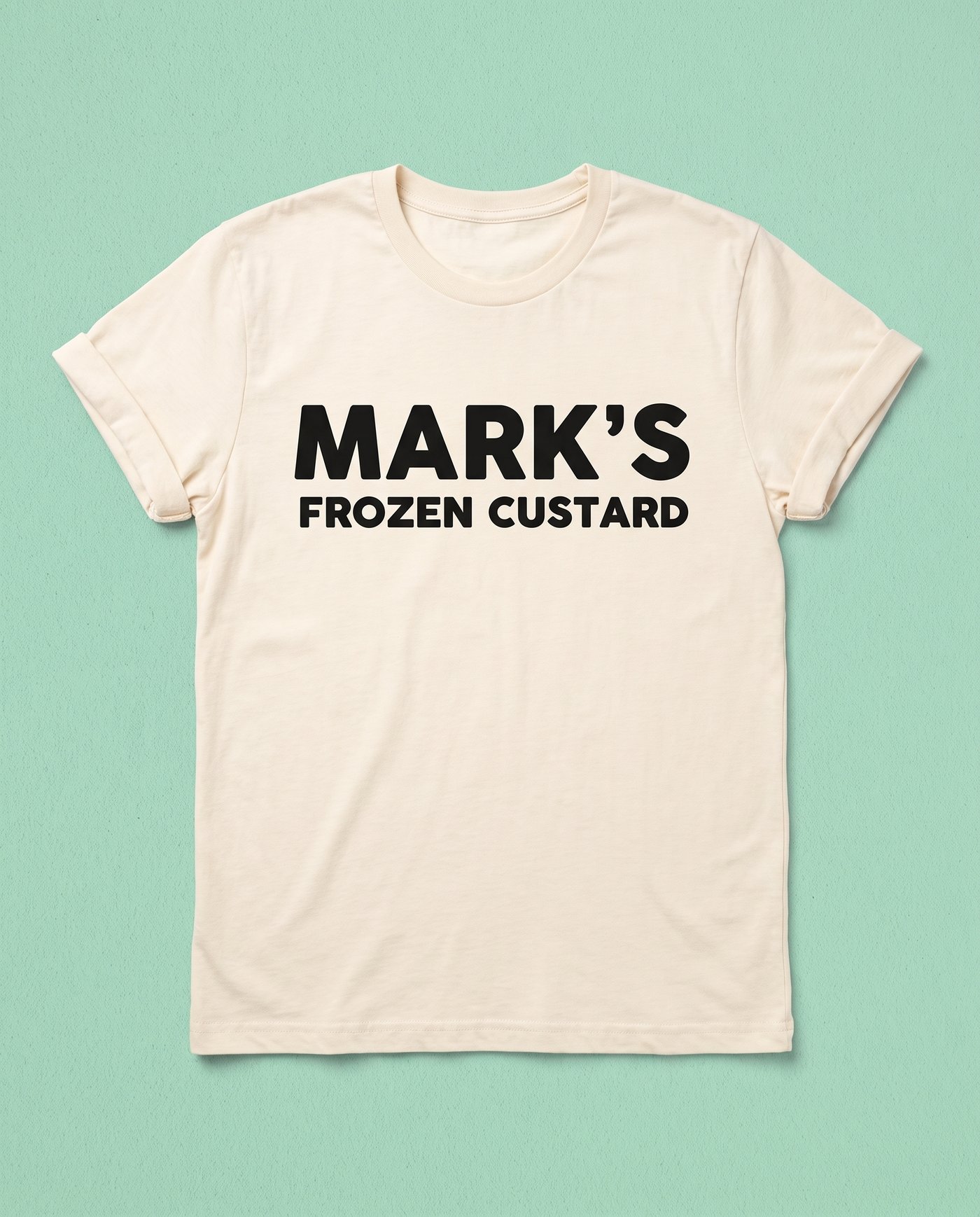 A cream t-shirt printed with the Mark’s wordmark on mint